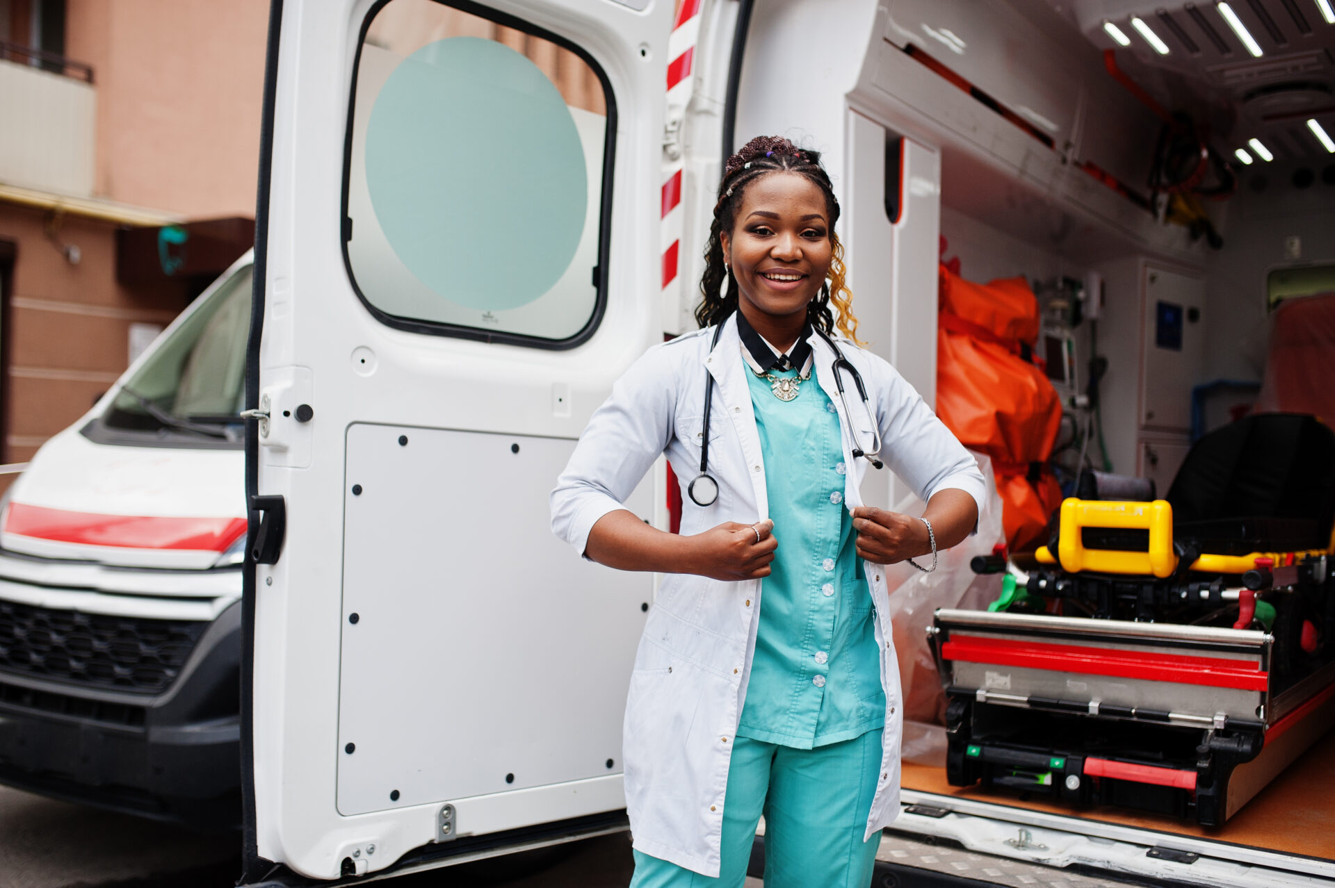 A woman in scrubs standing next to an ambulance.