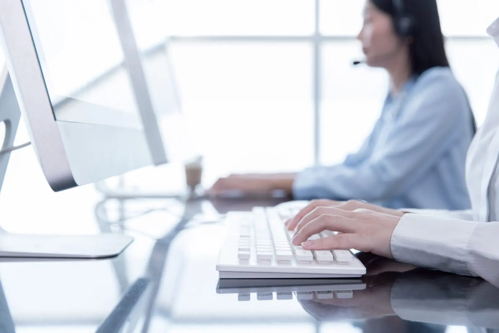 A person with headphones on sitting at a computer.