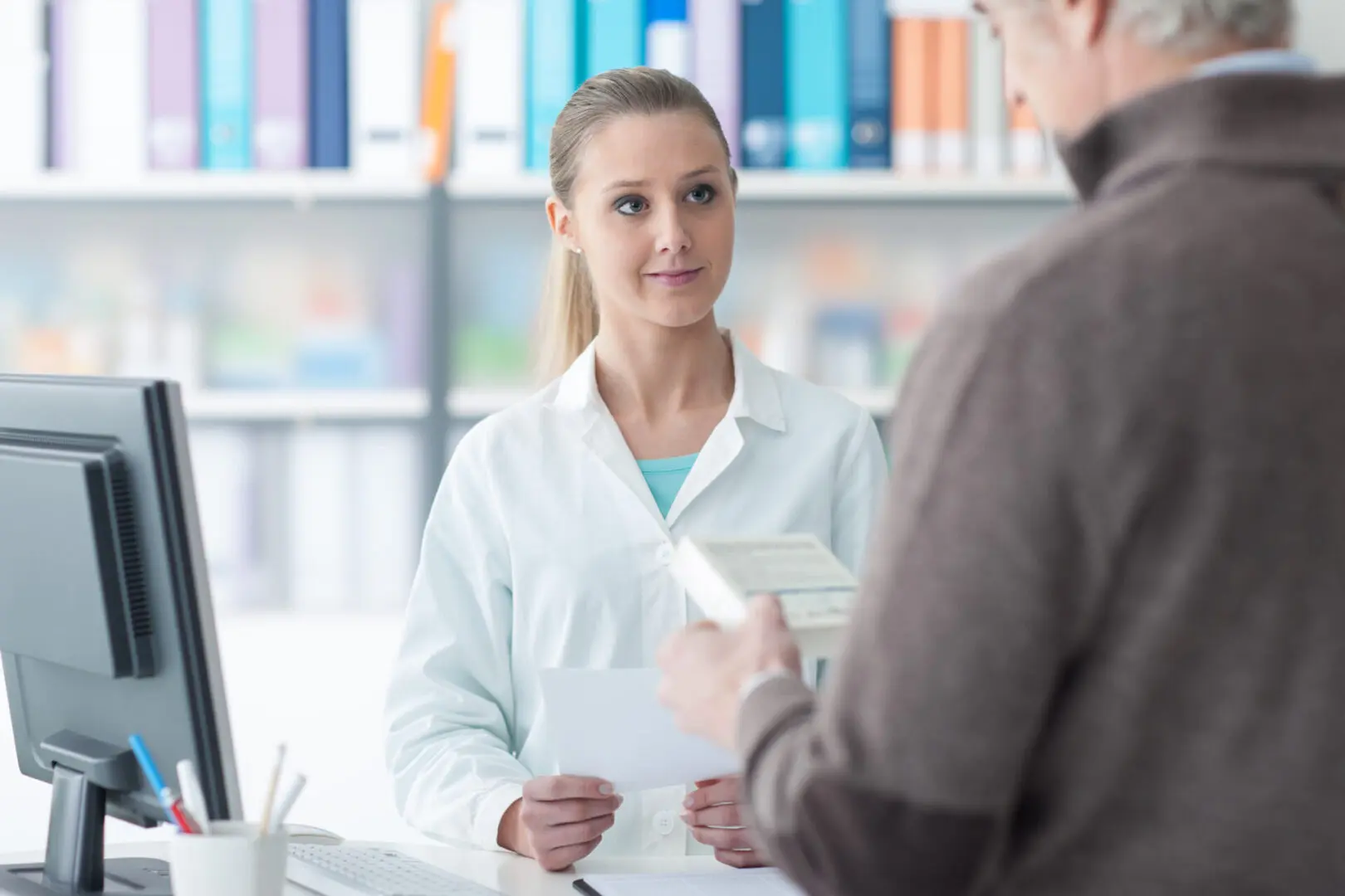 A woman in white lab coat holding papers near man.