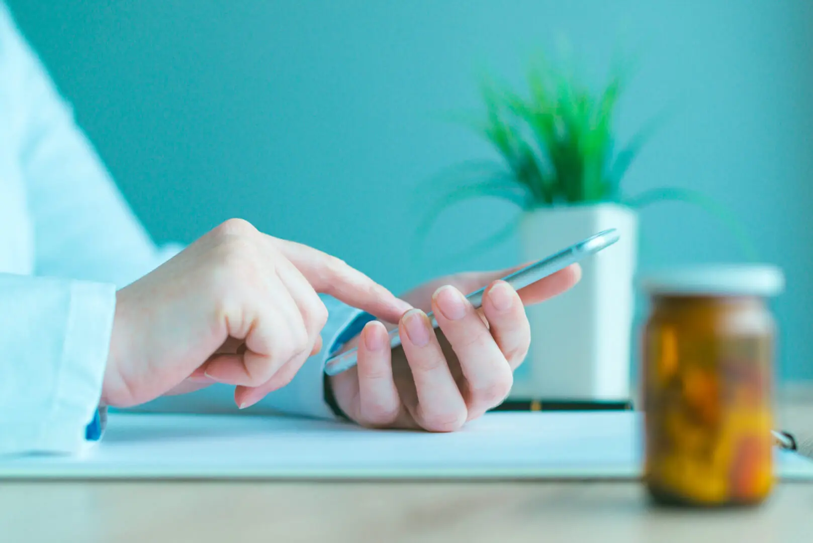 General practitioner using smartphone in office, modern mobile apps in healthcare and medicine, blue toned image