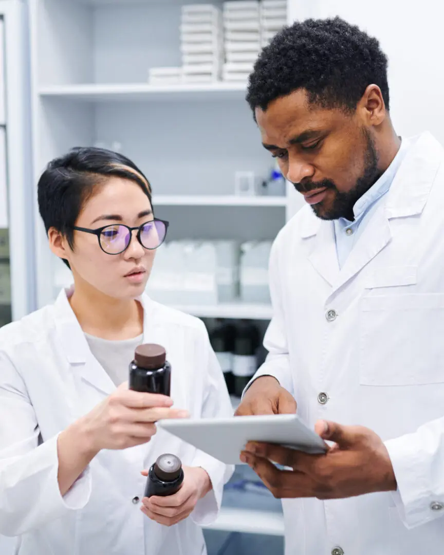 Two people in lab coats looking at a tablet.