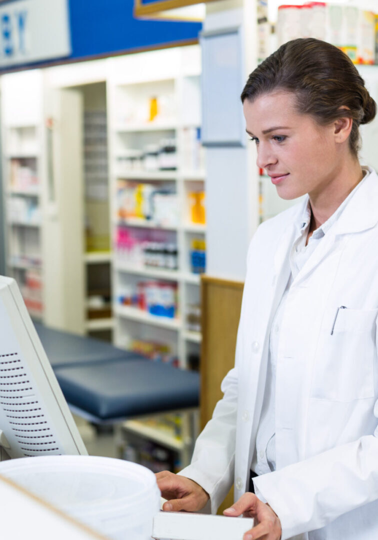 Pharmacist making prescription record through computer in pharmacy